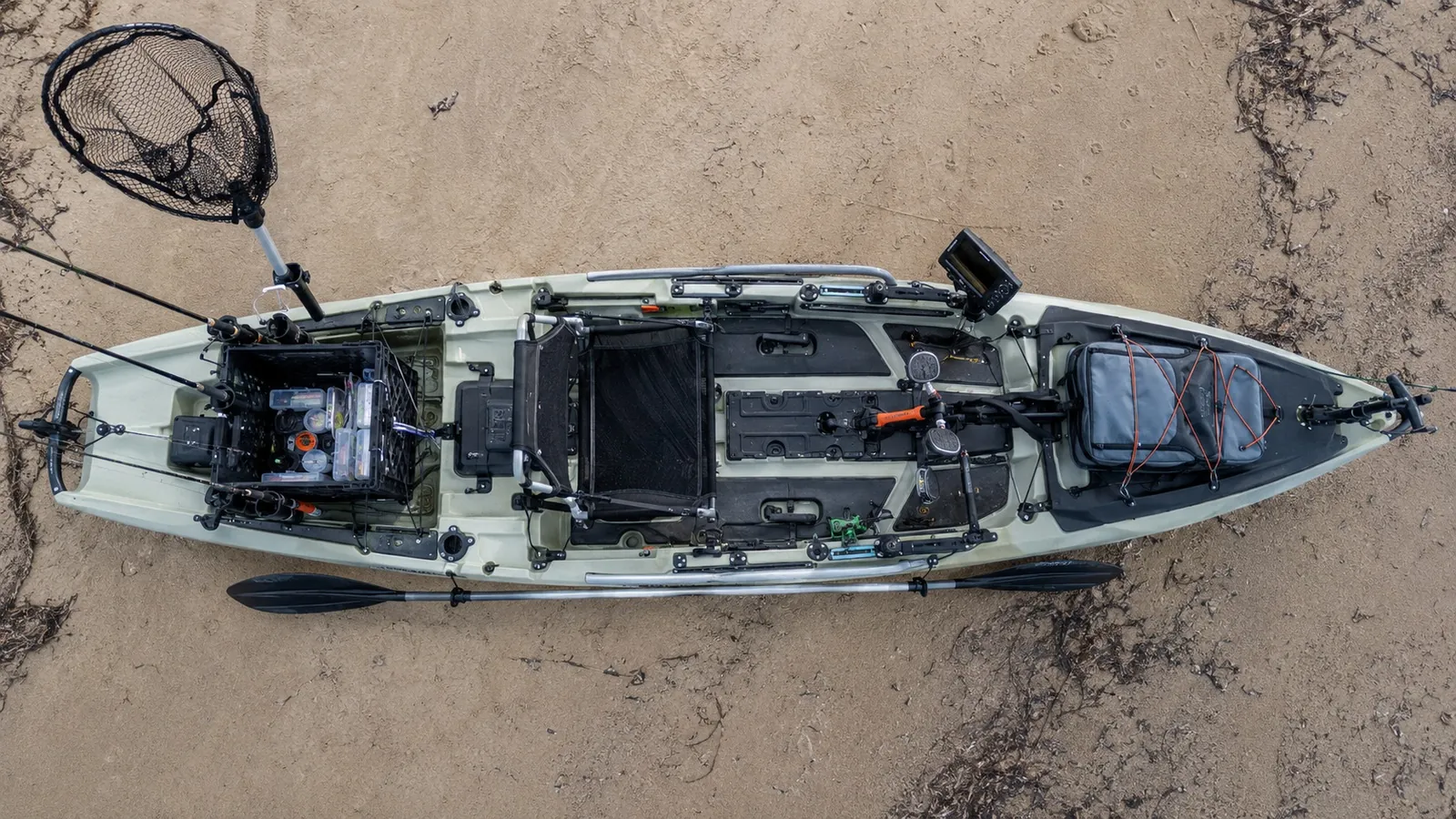 A fully rigged saltwater fishing kayak photographed from above on wet sand